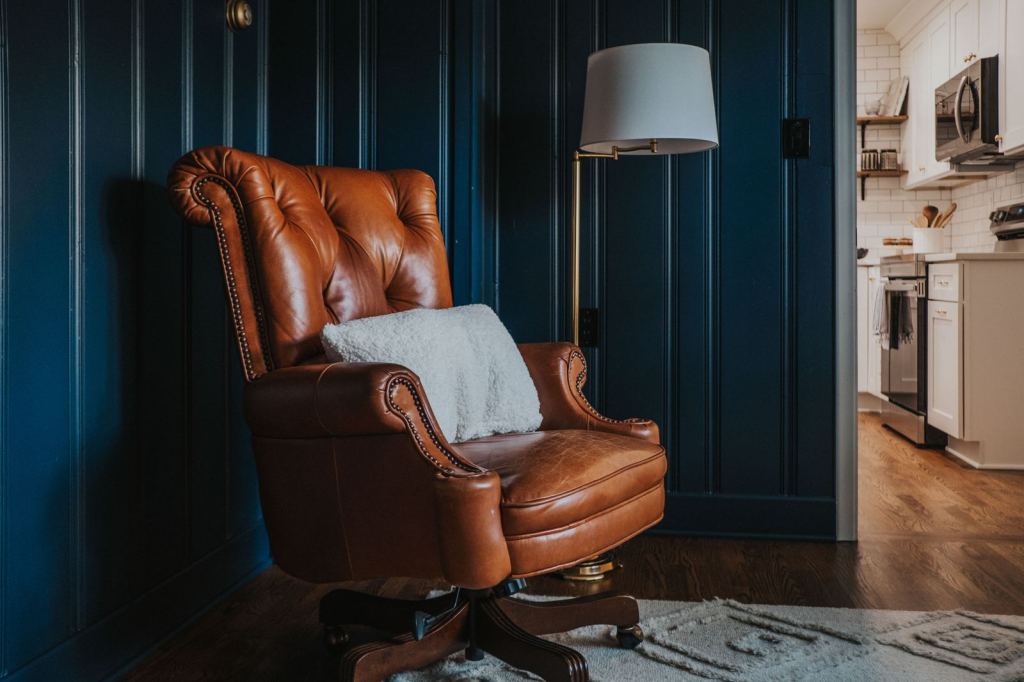 Cognac leather chair against a deep navy paneled wall