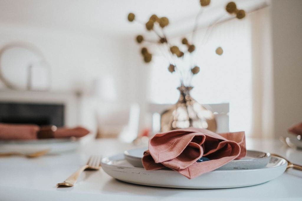 Table set with a rose linen napkin, gold flatware and dried flowers