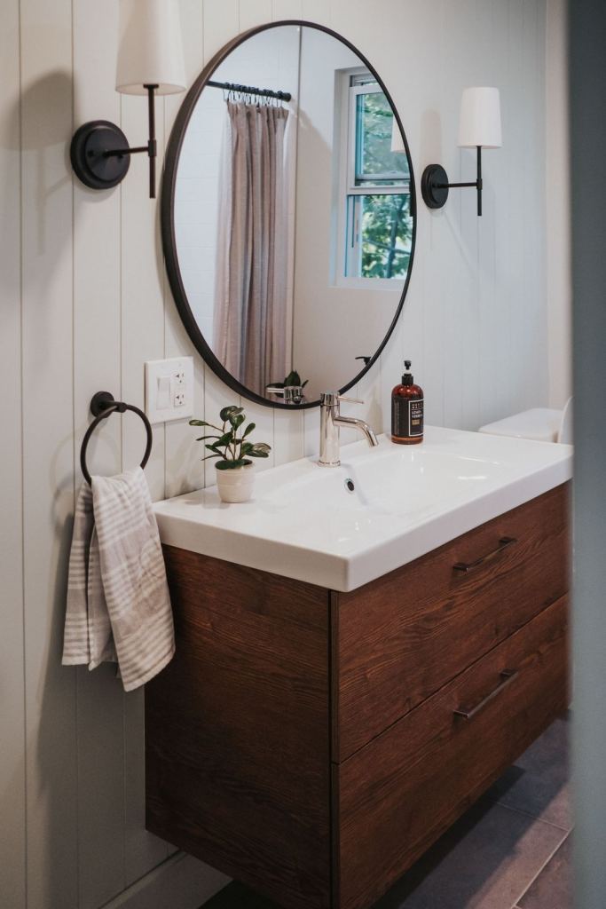 Powder bath with walnut vanity, round black mirror and white shiplap