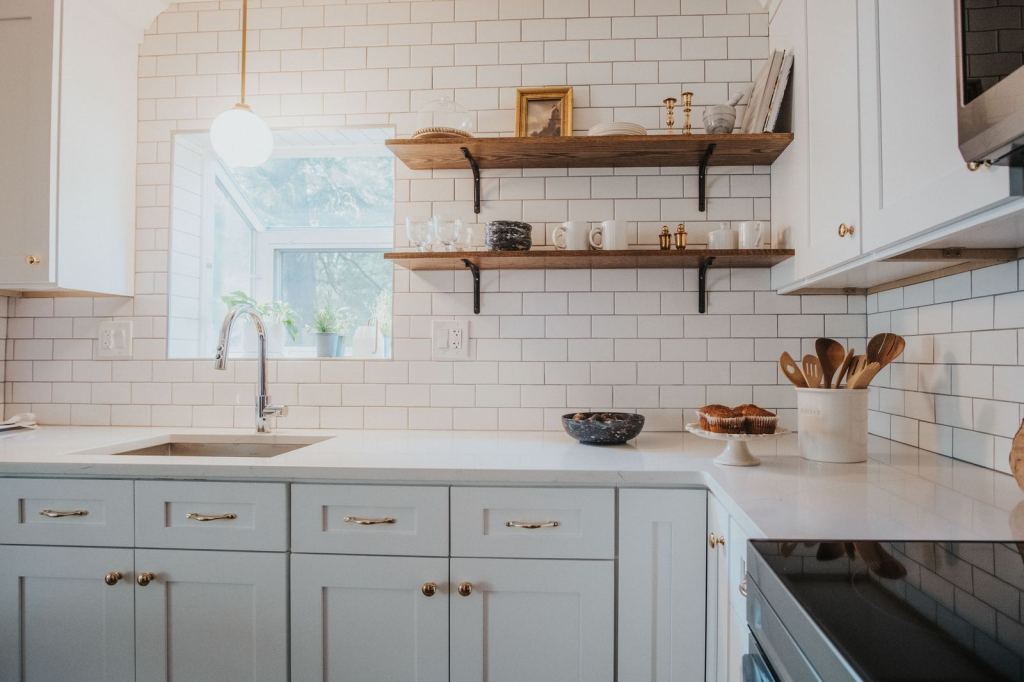 Bright kitchen with subway tile, open walnut shelves and sage cabinets