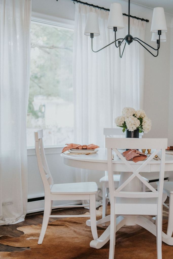 Round white table and chairs under a sculptural chandelier