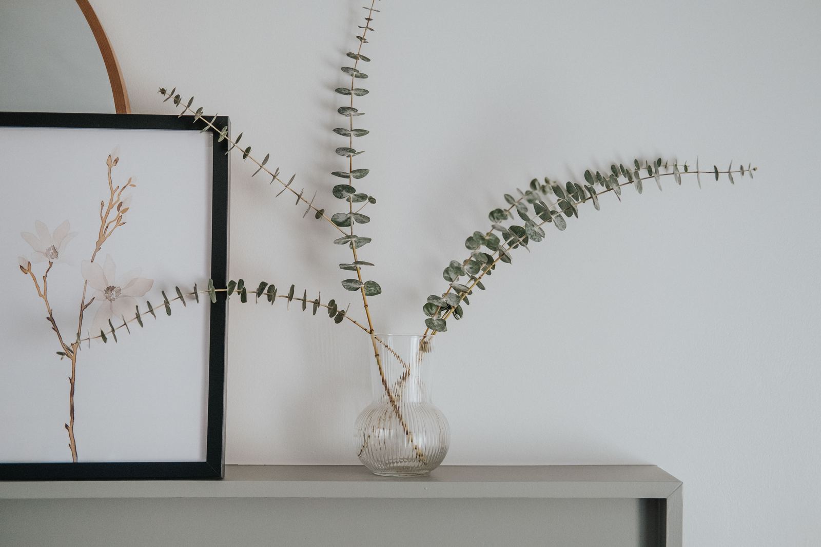 Eucalyptus branch and a framed print on a pale mantel