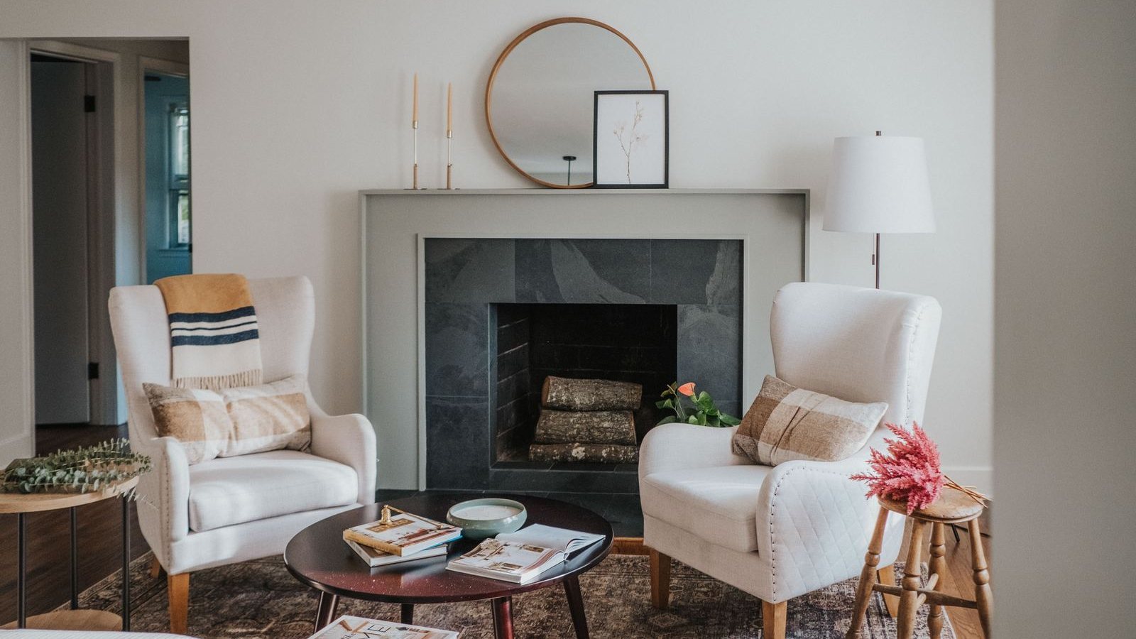 Living room with two cream wingback chairs facing a slate fireplace