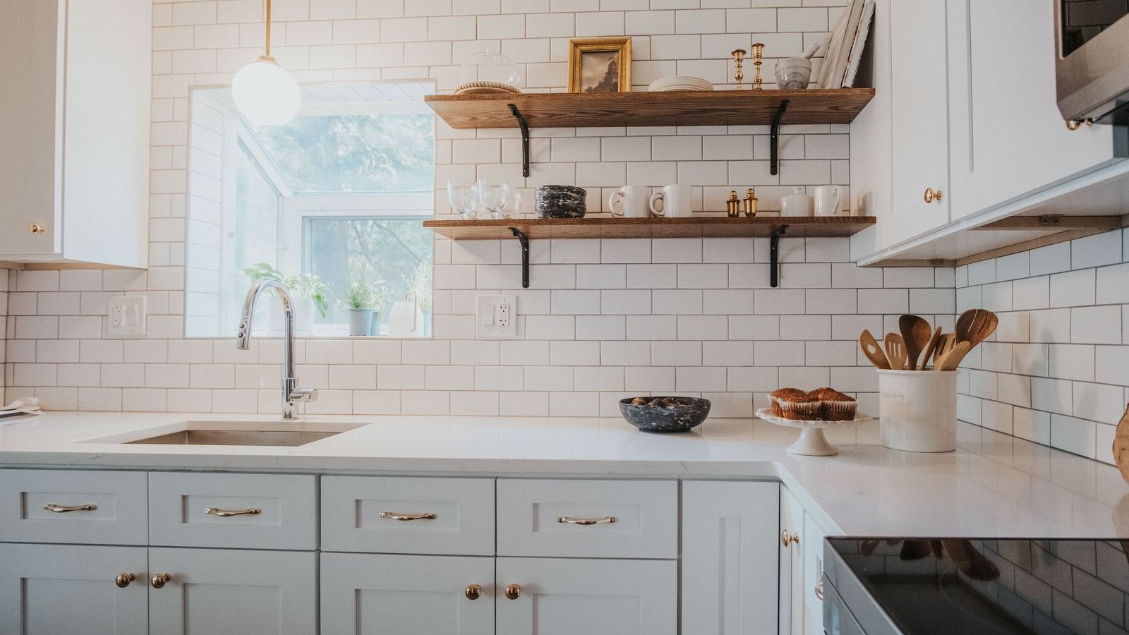 Bright kitchen with subway tile, open walnut shelves and sage cabinets